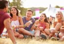 Friends sitting on grass and eating at music festival